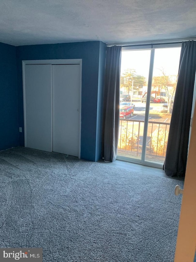 unfurnished bedroom featuring a closet, multiple windows, carpet flooring, and a textured ceiling