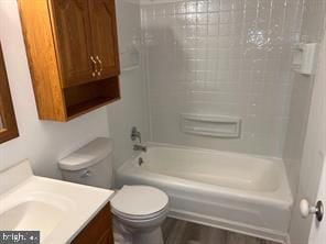 full bathroom featuring vanity, hardwood / wood-style flooring, toilet, and tiled shower / bath combo