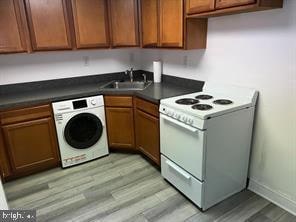 kitchen with washer / clothes dryer, sink, light hardwood / wood-style flooring, and white electric stove