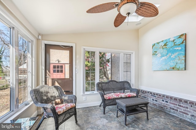 living area with ceiling fan, plenty of natural light, brick wall, and lofted ceiling