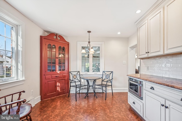 kitchen featuring white cabinets, tasteful backsplash, hanging light fixtures, and stone countertops