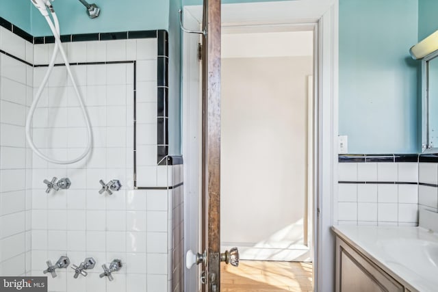 bathroom featuring a tile shower, vanity, and hardwood / wood-style floors