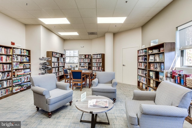 living area with a towering ceiling and a drop ceiling