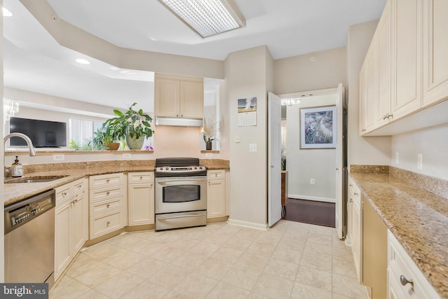 kitchen featuring light stone countertops, cream cabinetry, stainless steel appliances, and sink