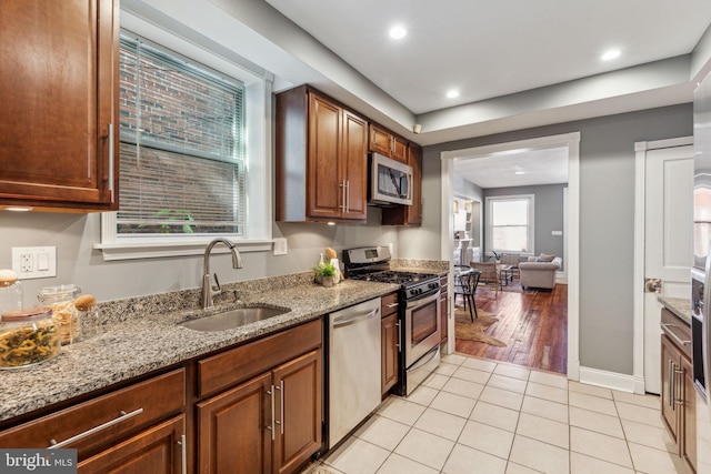 kitchen featuring light stone countertops, sink, stainless steel appliances, and light wood-type flooring