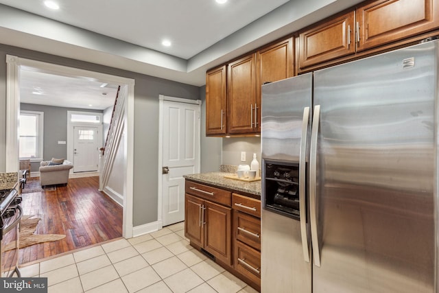 kitchen featuring appliances with stainless steel finishes, light hardwood / wood-style floors, and dark stone countertops