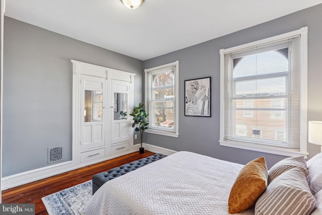 bedroom with multiple windows and dark wood-type flooring