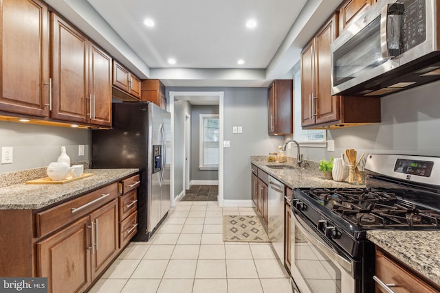 kitchen featuring light tile patterned flooring, light stone counters, sink, and appliances with stainless steel finishes