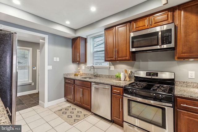 kitchen with light stone counters, light tile patterned floors, sink, and appliances with stainless steel finishes