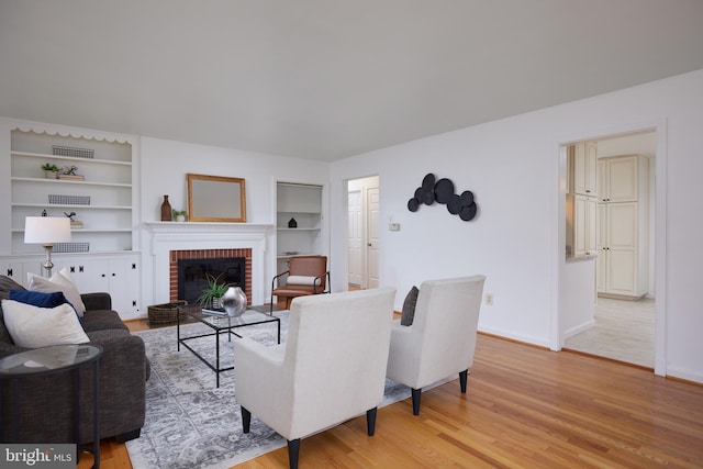 living room with a fireplace, light hardwood / wood-style flooring, and built in shelves