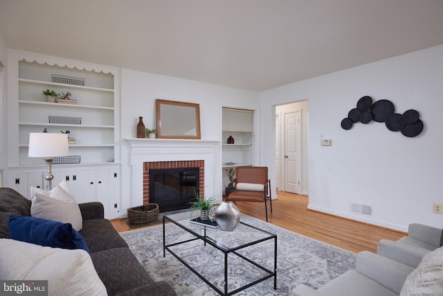 living room with a fireplace, light hardwood / wood-style flooring, and built in features