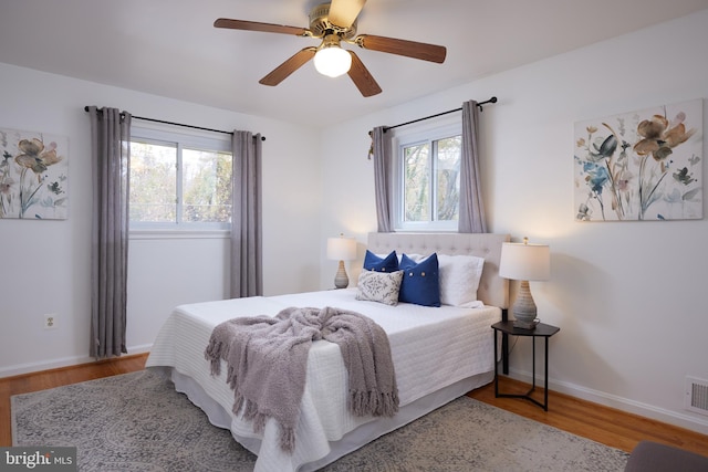 bedroom featuring ceiling fan, wood-type flooring, and multiple windows