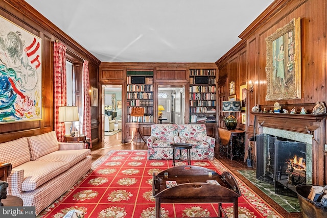 living room featuring built in shelves, a fireplace, wooden walls, and hardwood / wood-style floors