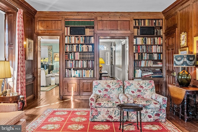 living area featuring hardwood / wood-style flooring, built in shelves, and wood walls