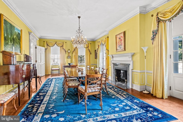 dining area featuring hardwood / wood-style flooring, ornamental molding, a chandelier, and a high end fireplace