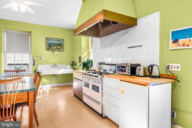 kitchen featuring sink, range hood, tasteful backsplash, white cabinets, and range with two ovens