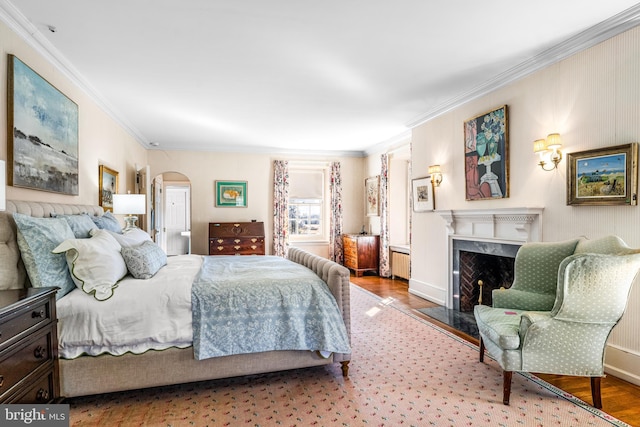 bedroom with hardwood / wood-style floors, a premium fireplace, ornamental molding, and radiator heating unit