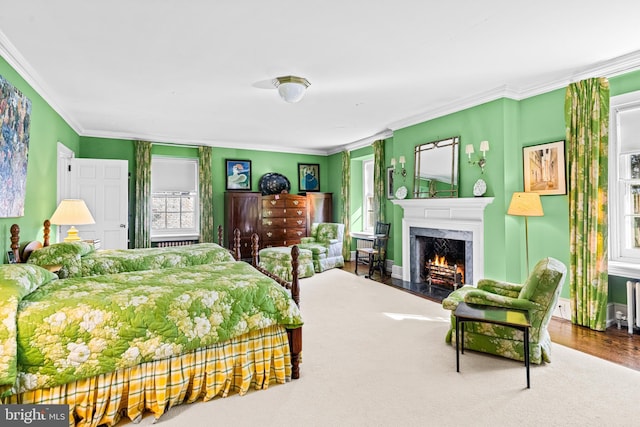 bedroom with multiple windows, crown molding, a high end fireplace, and hardwood / wood-style flooring