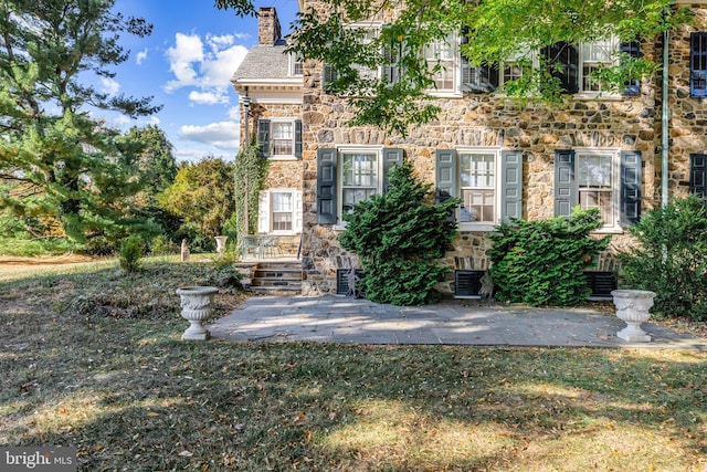 property entrance featuring a patio, a lawn, and central air condition unit