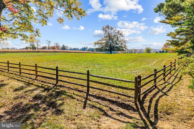 view of gate with a lawn and a rural view