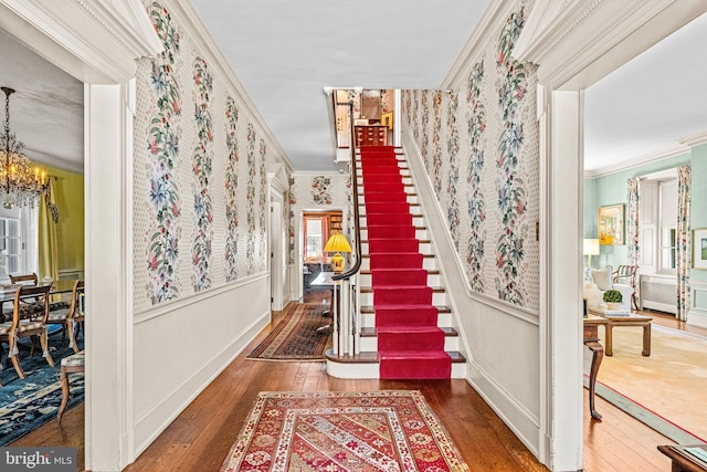 staircase featuring crown molding, hardwood / wood-style floors, and a notable chandelier