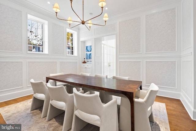 dining area featuring wood-type flooring, an inviting chandelier, and ornamental molding