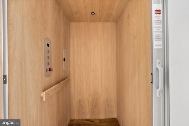 interior details with wooden walls, elevator, and wooden ceiling