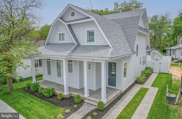 view of front of house with central AC unit, a porch, and a front lawn