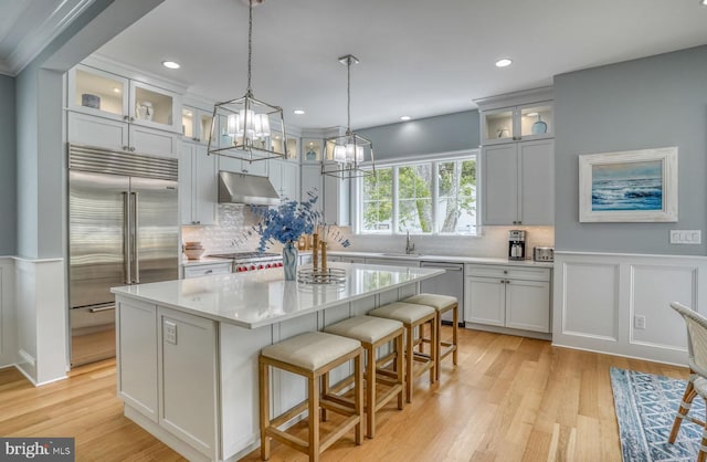 kitchen featuring appliances with stainless steel finishes, tasteful backsplash, decorative light fixtures, light hardwood / wood-style flooring, and a center island