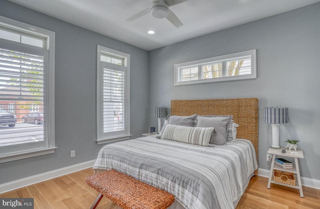 bedroom featuring hardwood / wood-style flooring, ceiling fan, and multiple windows