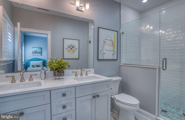 bathroom featuring a shower with door, vanity, and toilet