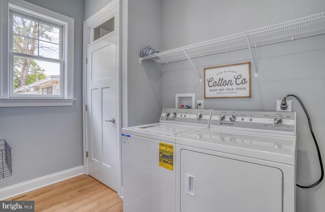 clothes washing area featuring separate washer and dryer and light hardwood / wood-style flooring