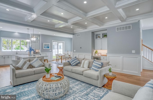 living room featuring coffered ceiling, beam ceiling, and light hardwood / wood-style flooring