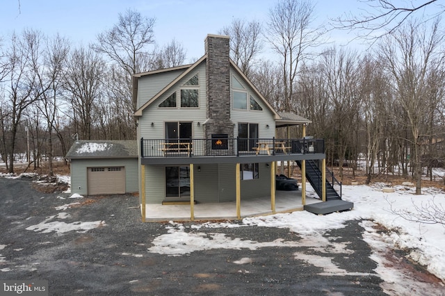 snow covered rear of property with a deck and a garage