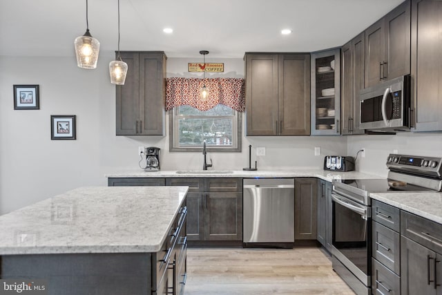 kitchen featuring light wood-type flooring, stainless steel appliances, hanging light fixtures, and sink