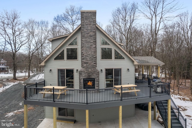 snow covered rear of property with a wooden deck