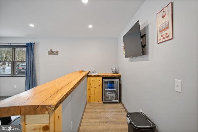 bar with wood counters, light wood-type flooring, and wine cooler