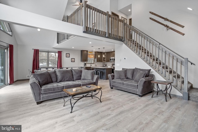 living room with ceiling fan, high vaulted ceiling, and light hardwood / wood-style floors