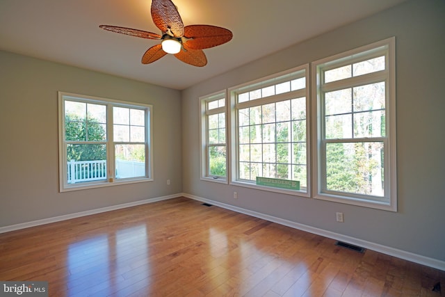 empty room with ceiling fan, a healthy amount of sunlight, and light hardwood / wood-style floors