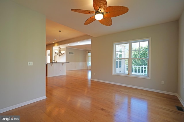 unfurnished room featuring ceiling fan with notable chandelier and light wood-type flooring