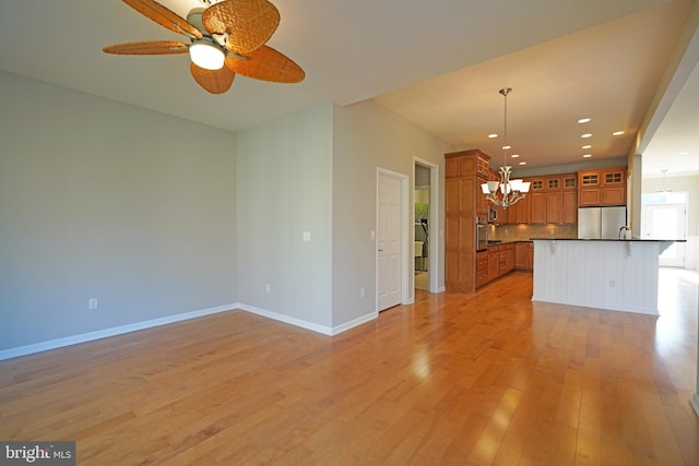 kitchen featuring a kitchen island with sink, light hardwood / wood-style flooring, ceiling fan, decorative light fixtures, and stainless steel refrigerator