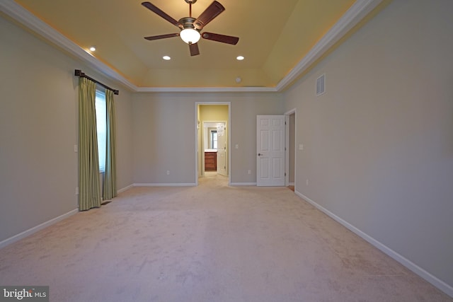 unfurnished room with ceiling fan, a raised ceiling, ornamental molding, and light carpet