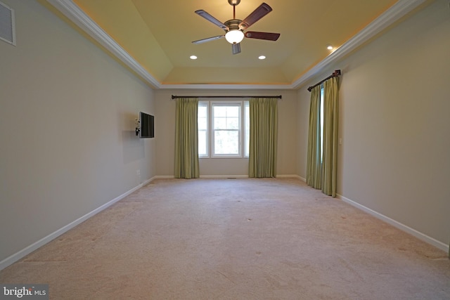 spare room with a tray ceiling, light colored carpet, and ornamental molding