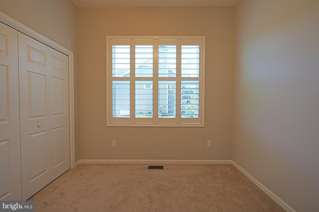 unfurnished bedroom featuring a closet and light colored carpet