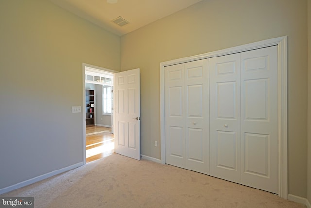 unfurnished bedroom with light carpet and a closet