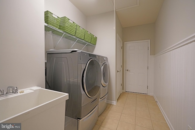 laundry room featuring light tile patterned floors, washer and clothes dryer, and sink