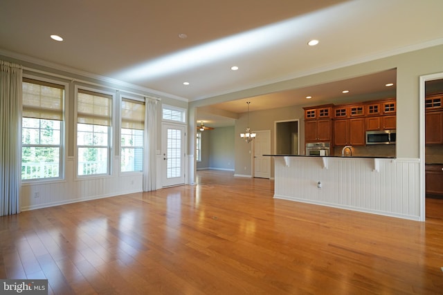 unfurnished living room featuring a chandelier, light hardwood / wood-style floors, and ornamental molding