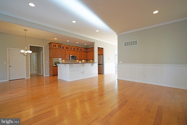 unfurnished living room with light hardwood / wood-style floors, an inviting chandelier, and ornamental molding