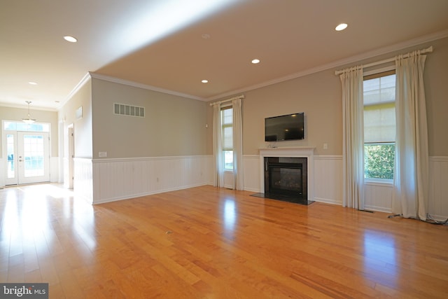 unfurnished living room featuring a chandelier, crown molding, and light hardwood / wood-style flooring