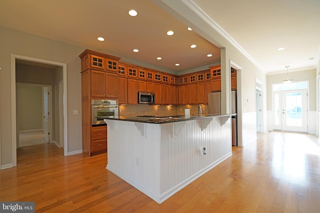 kitchen featuring light hardwood / wood-style floors, crown molding, stainless steel appliances, and a kitchen island with sink